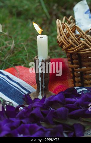 Primo piano candela che brucia in legno accanto a picnic woven basket concept foto Foto Stock