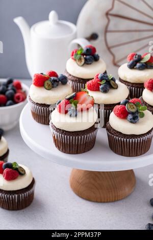 Cupcake al cioccolato con crema di formaggio glassa e frutti di bosco freschi d'estate Foto Stock