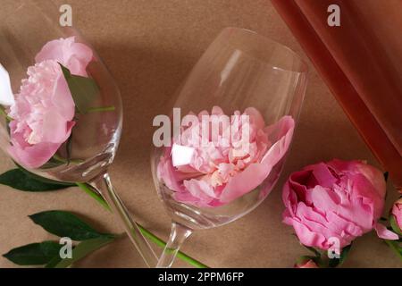 Bottiglia di vino rosato, bicchieri e belle peonie rosa su sfondo marrone, primo piano Foto Stock