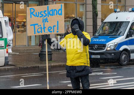 BERLINO - 25 FEBBRAIO 2023: Attivista ucraino con un poster in tedesco - 'la Russia è un criminale' di fronte all'ambasciata russa su Unter der Linden. Foto Stock