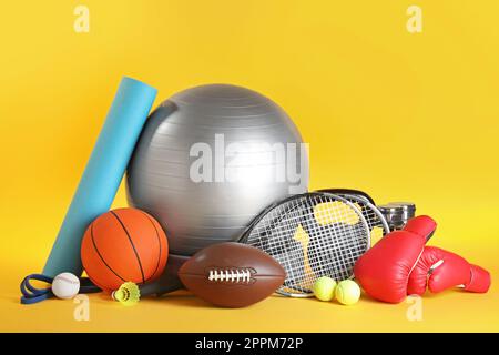 Set di diverse attrezzature sportive su sfondo giallo Foto Stock