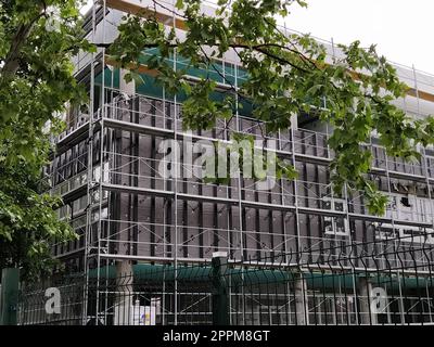 Sremska Mitrovica, Serbia, 30 maggio 2020. Costruzione di un nuovo edificio scolastico. Impalcature sulla facciata. Recinzione metallica. Finire il lavoro Foto Stock