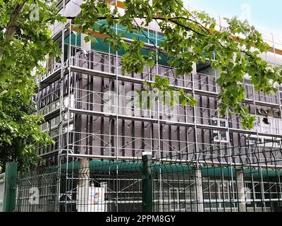 Sremska Mitrovica, Serbia, 30 maggio 2020. Costruzione di un nuovo edificio scolastico. Impalcature sulla facciata. Recinzione metallica. Finire il lavoro Foto Stock