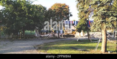 Sremska Mitrovica, Serbia, 13 agosto 2020. Smantellamento e demolizione della vecchia scuola che prende il nome da Jovan Popovic. Pezzi di cemento e armatura sono appesi. I bulldozer stanno abbattendo i muri. Foto Stock