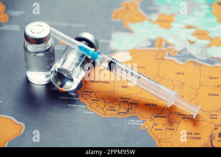 Siringa medica con un ago e un bollte con il vaccino sulla mappa del mondo. Foto Stock