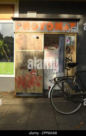 Foto verticale di una cabina fotografica in legno in stile vintage con una bicicletta parcheggiata di fronte ad essa Foto Stock