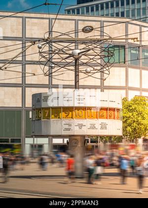 Famoso orologio mondiale ad Alexanderplatz, Berlino, Germania, con persone che camminano davanti, lunga esposizione, al tramonto, ripresa verticale Foto Stock