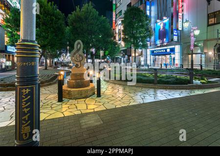 ikebukuro, giappone - dicembre 31 2012: Palo lampione di Sunshine Street di fronte a un monumento in marmo a forma di lacci alti all'uscita est della stazione di Ikebukuro a Tokyo di notte. Foto Stock