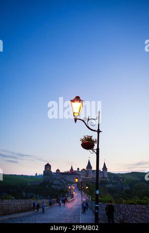 Kamianets-Podilskyi è una città romantica, con una splendida vista della città serale, le lanterne illuminano il ponte e la lanterna da vicino. Una pittoresca vista estiva dell'antico castello-fortezza di Kamianets-Podilskyi, regione di Khmelnytskyi, Ucraina. Foto Stock