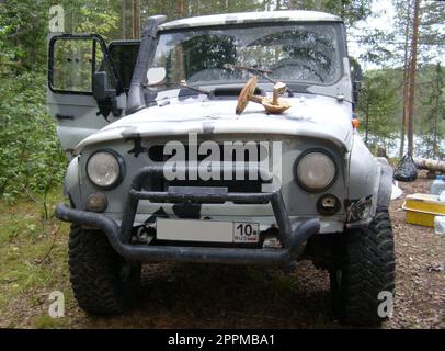 Carelia, Russia - 12 luglio 2019: Due enormi funghi giacciono sulla fuliggine di un'auto UAZ. Boletus, boletus e funghi vengono raccolti durante il fine settimana nella foresta. SUV con numeri di registrazione russi Foto Stock