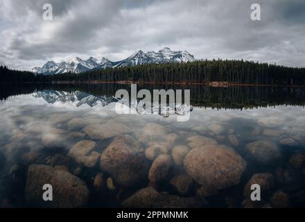 Lago Herbert in Alberta, Canada in una giornata nuvolosa con montagne mozzafiato e riflessi d'acqua Foto Stock