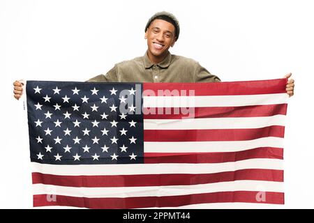 Allegro afro-americano ragazzo che tiene in mani bandiera americana, guardando la fotocamera e sorridendo isolato su sfondo bianco, Flag Day concetto Foto Stock