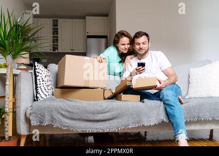 Una giovane coppia ha soddisfatto i clienti che hanno lasciato il feedback e il servizio di consegna di rating online utilizzando il telefono cellulare. Foto Stock