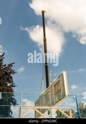 Il montaggio di una casa prefabbricata - parete è appeso alla gru Foto Stock