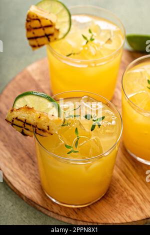 margarita di ananas alla griglia guarnita con spicchi di lime e timo Foto Stock