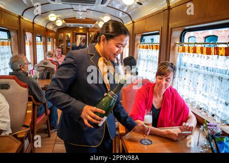 Serve champagne all'interno del treno di lusso Expreso de la Robla che viaggia attraverso Bilbao fino a Leon, nel nord della Spagna, in Europa. Interno del ristorante ca Foto Stock