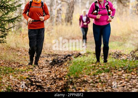 donne e uomini corridori correre maratona autunnale sentiero sulle foglie cadute nella foresta, corsa di corsa di fondo Foto Stock