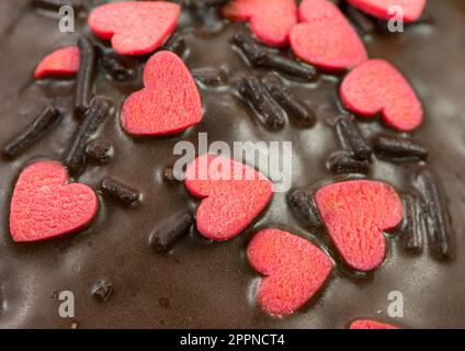 Dettaglio di un muffin al cioccolato con zucchero rosso cuori e spruzza Foto Stock