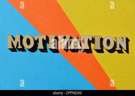 Motivazione, parola in lettere alfabetiche di legno isolate su sfondo luminoso e colorato Foto Stock