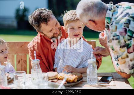 Famiglia multigenerazionale con barbecue all'aperto nel cortile. Foto Stock