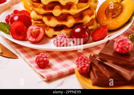 cialde, polvere con fragole, albicocche, ciliegie, succo di frutta e una tazza di caffè nero Foto Stock