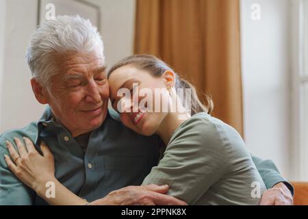 Nipote abbraccia suo nonno nella loro casa. Foto Stock