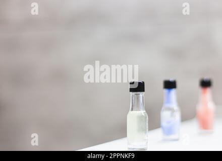 Tre bottigliette di crema colorata in fila con spazio copia. Prodotto benessere sul tavolo. Bagno. Prodotto cosmetico. Stili di vita sani. Foto Stock