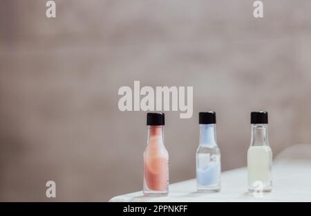 Tre bottigliette di crema colorata in fila con spazio copia. Prodotto benessere sul tavolo. Bagno. Prodotto cosmetico. Stili di vita sani. Foto Stock