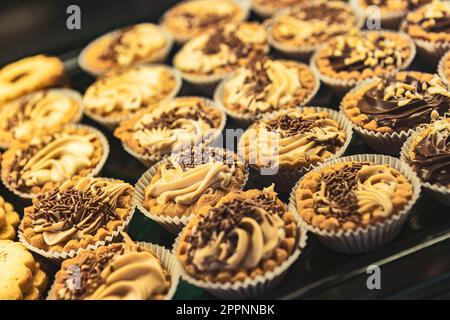 Una foto colorata di vari dessert e dolci in una vetrina panetteria. Perfetto per piatti, panetteria e dessert. Foto Stock