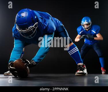 Due giocatori di calcio americani sono pronti per iniziare la partita su uno sfondo nero. Foto Stock