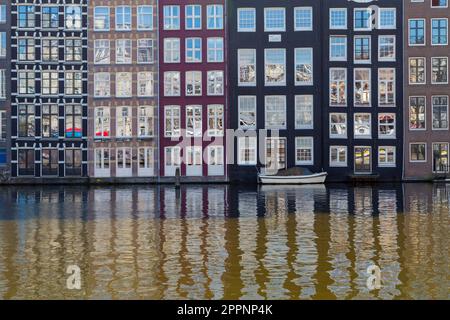 Case danzanti, edifici con riflessi nelle finestre di Damrak canale ad Amsterdam, Olanda, Paesi Bassi nel mese di aprile Foto Stock
