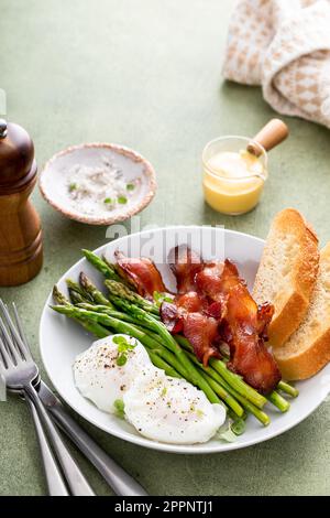Colazione sana con uova in camicia, pancetta e asparagi serviti con salsa di hollandaise Foto Stock