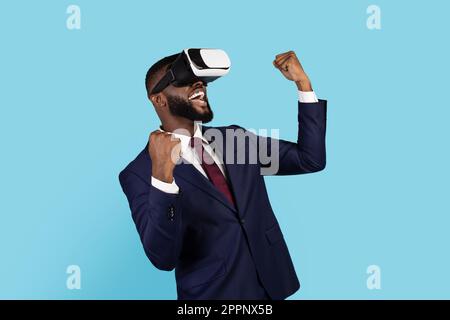 Tecnologie moderne. Gioioso uomo d'affari nero che indossa occhiali VR per celebrare il successo Foto Stock
