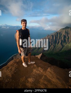 Uomo che fa trekking fino alla cima del Na Pali Coast state Park a Kauai, Hawaii al tramonto. Foto di alta qualità. Foto Stock