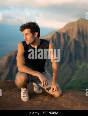 Uomo che fa trekking fino alla cima del Na Pali Coast state Park a Kauai, Hawaii al tramonto. Foto di alta qualità. Foto Stock