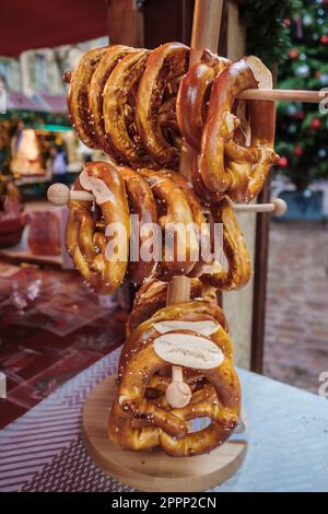 Il pretzel o bretzel è un tipo di pasta da forno che viene comunemente formata in un nodo. Pretzel impilati su uno stand di legno in una resta francese Foto Stock