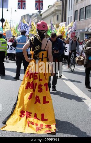 Londra, Regno Unito. 24th aprile 2023. Una ragazza indossa un abito giallo drammatico con un logo Shell e sul retro le parole Shell deve cadere. L'ultimo di un'azione di quattro giorni di Extinction Rebellion, The Big One, Unite per sopravvivere, migliaia di persone hanno marciato dalla Corte Suprema passando per Downing Street, Trafalgar Square, lungo lo Strand e sulla sede centrale di Shell in marzo per porre fine ai combustibili fossili. I manifestanti stavano cantando Shell deve cadere. Credit: Maureen McLean/Alamy Live News Foto Stock