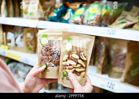 Cibo, generi alimentari e shopping con noci in supermercato per la salute,  la nutrizione e la vendita al dettaglio offerta. Scelta, stoccaggio e vegan  con prodotti a grani in zero Foto stock 