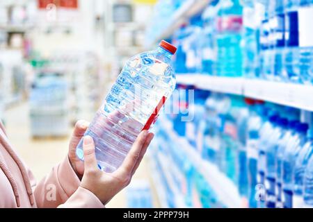 Bottiglia di plastica acqua potabile in mani acquirente in negozio Foto Stock