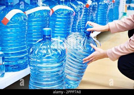 Bottiglie di acqua potabile per dispenser nelle mani del negozio Foto Stock