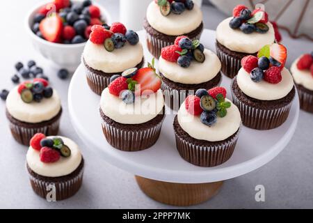 Cupcake al cioccolato con crema di formaggio glassa e frutti di bosco freschi Foto Stock