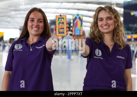 USO EDITORIALE SOLO qui per aiutare i membri del team Georgina Gallop (a sinistra) e Isabella Shanks (a destra) a svelare la targhetta commemorativa per i bagagli di Heathrow progettata dall’artista Morag Myerscough per celebrare l’incoronazione di Re Carlo III, che sarà consegnata ai passeggeri dal 1 al 10 maggio. Data immagine: Lunedì 24 aprile 2023. Foto Stock