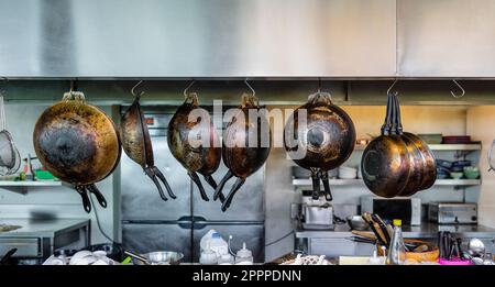 Molte padelle appese in cucina, primo piano Foto Stock