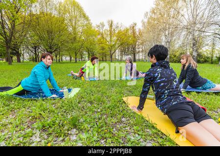 Gruppo misto di donne che fanno yoga al parco Foto Stock