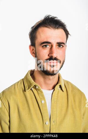 Classico ritratto frontale di un uomo caucasico con barba e baffi, marrone scuro con occhi blu, con camicia beige fustagno. Isolato contro il bianco Foto Stock