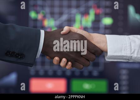 Primo piano dei mediatori che scuotono le mani per concludere un contratto durante il commercio delle azioni nell'ufficio di mediazione Foto Stock
