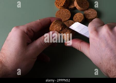 La mano di un uomo tiene i tappi tagliati e li taglia. Preservazione dell'ecologia del pianeta. Materie prime per il riutilizzo. Protezione ambientale. Foto Stock