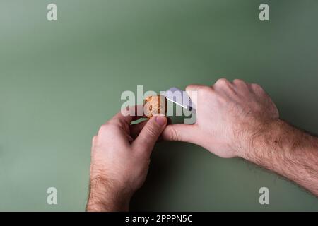 La mano di un uomo tiene i tappi tagliati e li taglia. Preservazione dell'ecologia del pianeta. Materie prime per il riutilizzo. Protezione ambientale. Foto Stock