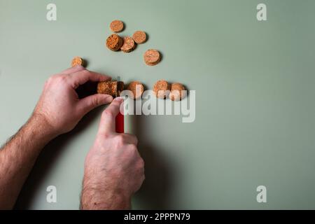 La mano di un uomo tiene i tappi tagliati e li taglia. Preservazione dell'ecologia del pianeta. Materie prime per il riutilizzo. Protezione ambientale. Foto Stock