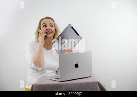 Banner per gadget spazio per testo donna che tiene tablet e telefono stand vicino laptop chiamate dice ridere pleases sincero iPhone gadget iPad MacBook telefono iPhone 13 Pro Max Ucraina Vinnitsa 2023 Foto Stock